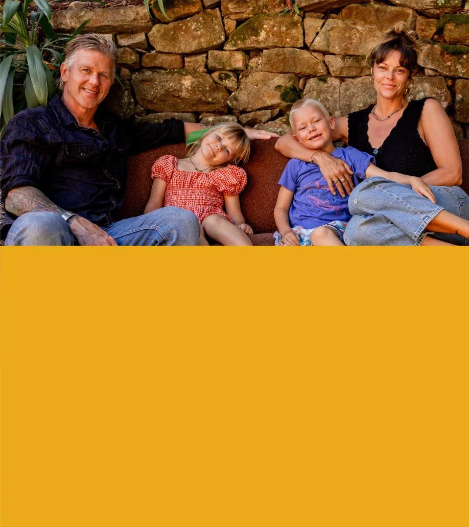 Family of four sitting on a couch against a stone wall.