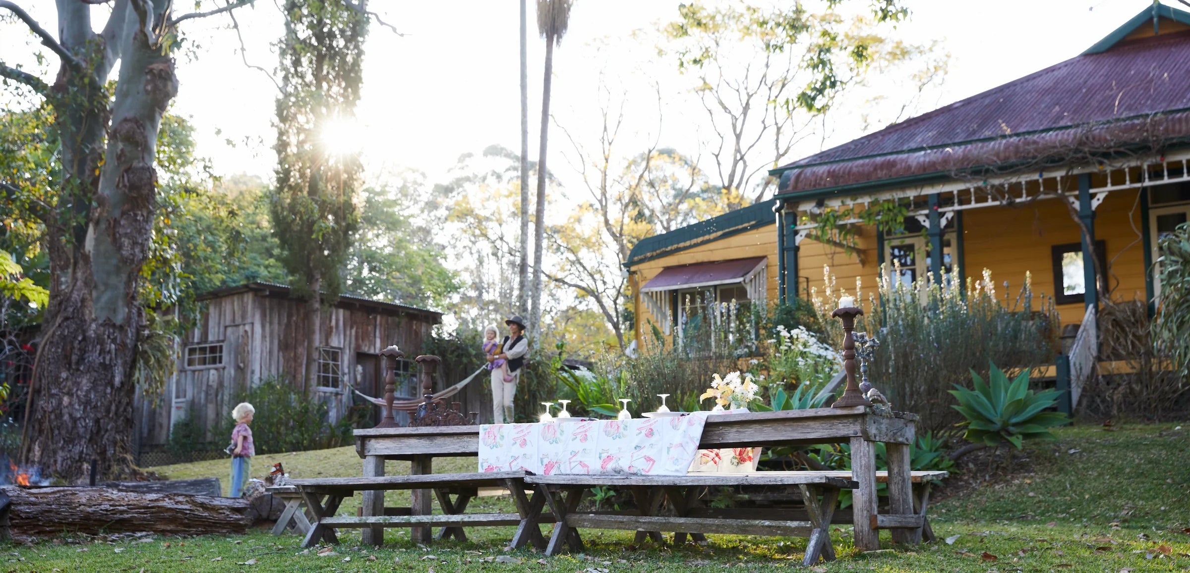 Outdoor setting with a picnic table, house, and people in a garden.